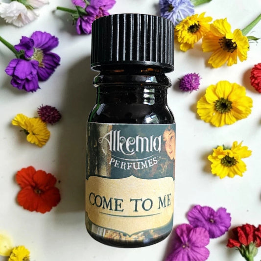 A small amber glass perfume bottle with a black ribbed cap and a vintage-style label reading 'Alkemia Perfumes' and 'COME TO ME', surrounded by scattered colorful flowers on a white background.
Alkemia Come To Me fragrance samples UK 1ml sample available 