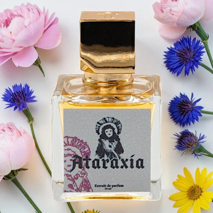 A square glass perfume bottle with a metallic gold cap and a gray label reading 'Ataraxía Extrait de parfum 50 ml', surrounded by pink and blue flowers on a white background. Ataraxia My Doll's Makeup| Fragrance Sample UK