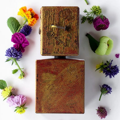 Two vintage, hand-painted wooden boxes stacked vertically on a white background, surrounded by colorful artificial flowers.
Filippo Sorcinelli Reliqvia | Fragrance Samples UK
