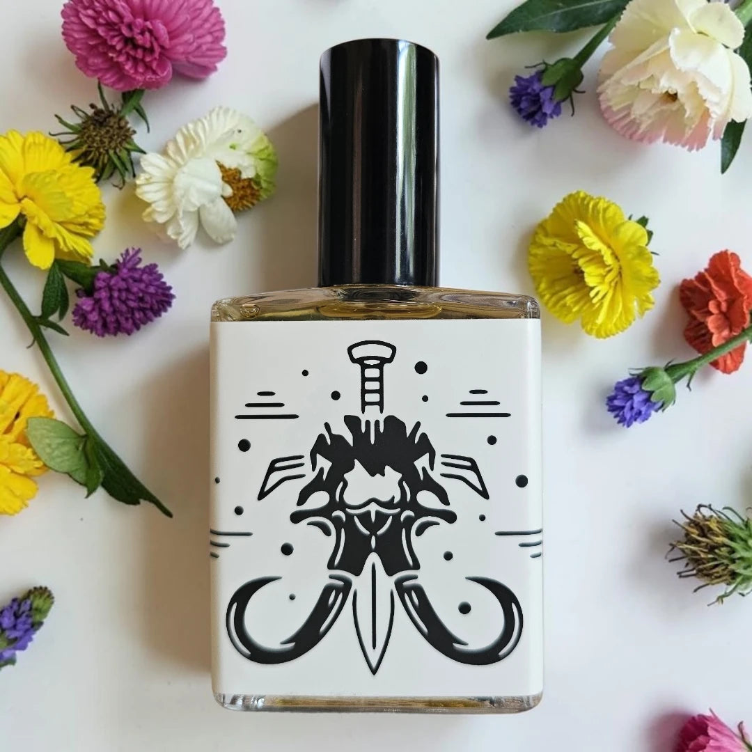 A square glass bottle with a black cap and a white label featuring a black graphic of a dagger, surrounded by colorful flowers on a white background.
House Of Mammoth You & I (Will Die) | Fragrance Samples UK 1ml 2ml 5ml samples available 
