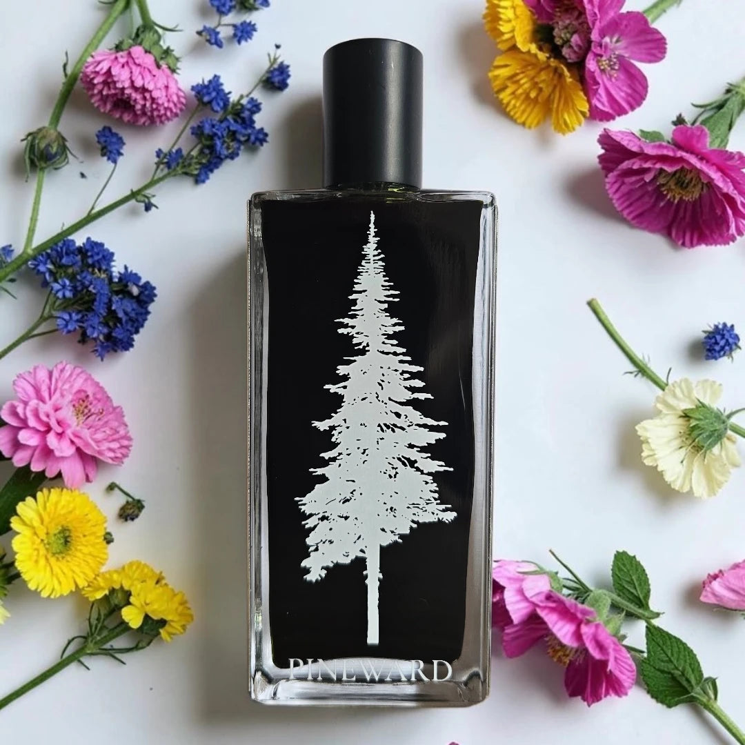 A rectangular glass perfume bottle with a black label featuring a white pine tree and the brand name 'PINEWARD' at the bottom, surrounded by colorful flowers on a white background.
Pineward Eldritch | Fragrance Samples UK available in 1ml 2ml 5ml samples 