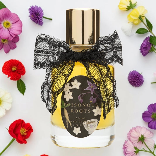 A 50 ml bottle of Poisonous Roots Eau de Parfum with a gold cap, decorated with a black lace bow. The bottle is filled with yellow liquid and features a black label with white and purple floral illustrations. Sorce poisonous Roots| Fragrance Samples UK 1ml 2ml and 5ml perfume samples available 
