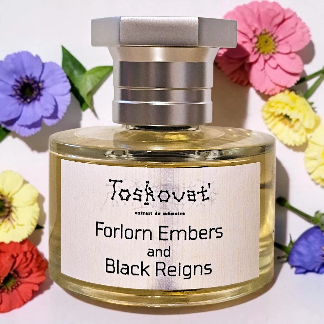 A bottle of Toshovat Forlorn Embers and Black Reigns scented candle wax or fragrance, featuring a silver cap and a white label, set against a white background decorated with colorful flowers. Toskovat Forlorn Embers And Black Reigns | Fragrance Samples UK available in 1ml, 2ml & 5ml