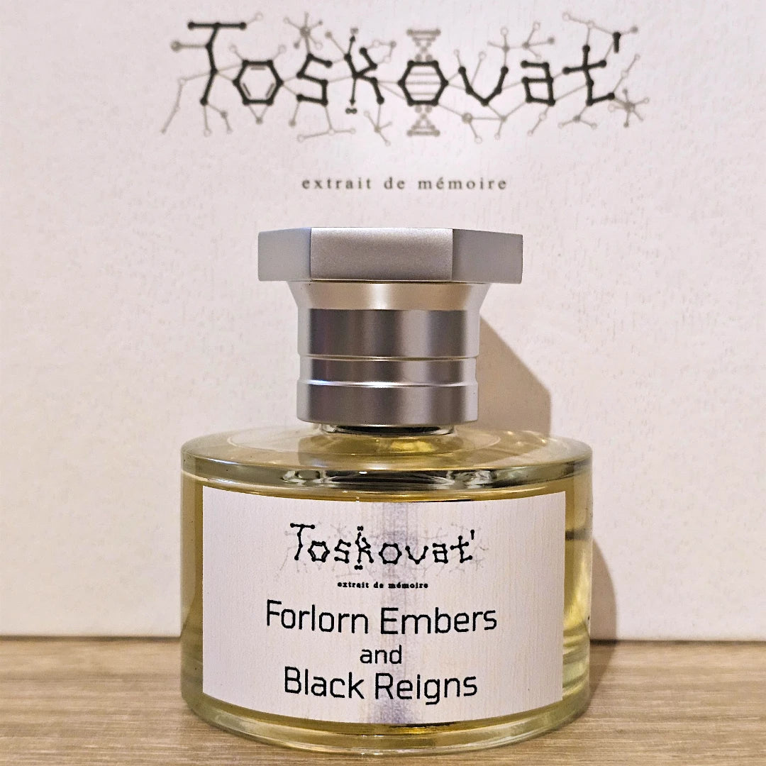 A bottle of Toskovat 'Forlorn Embers and Black Reigns' perfume with a silver cap and white label, set against a textured beige background with the brand name 'Toskovat' and 'extrait de mémoire' printed above.