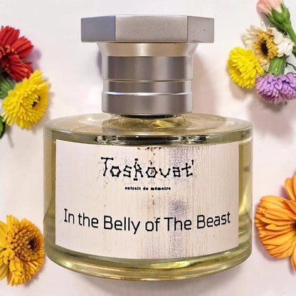 A bottle of Toskovat 'In the Belly of The Beast' perfume with a silver cap and a white label, styled with colorful flowers on a white background. Toskovat In the Belly of the Beast | Fragrance Samples UK 1ml 2ml and 5ml perfume samples available 