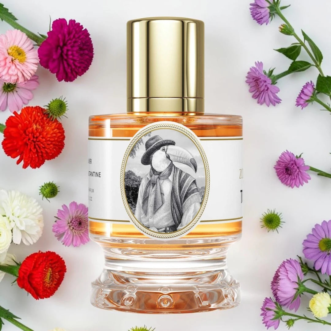 Zoologist Toucan | Fragrance Samples UK available in 1ml, 2ml & 5ml
A clear glass perfume bottle with a shiny gold cap and a white label featuring a black-and-white portrait, surrounded by colorful flowers on a white background.