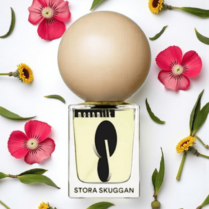 Perfume bottle labeled 'Stora Skuggan' surrounded by flowers and leaves on a white background